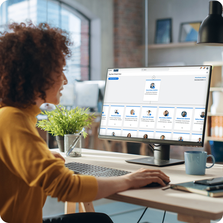 A woman with curly hair views an organizational chart on a computer screen in an office.